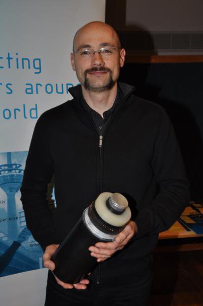 Ein Mann in schwarzem Hemd, präsentiert zufrieden ein dickes Stück von einem Kabel.