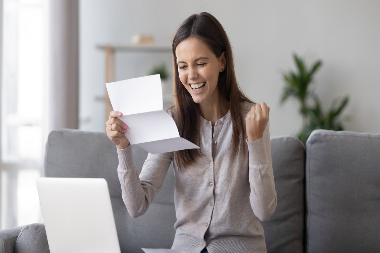 1126400322 junge Frau mit Brief in der Hand, über den sie sich freut