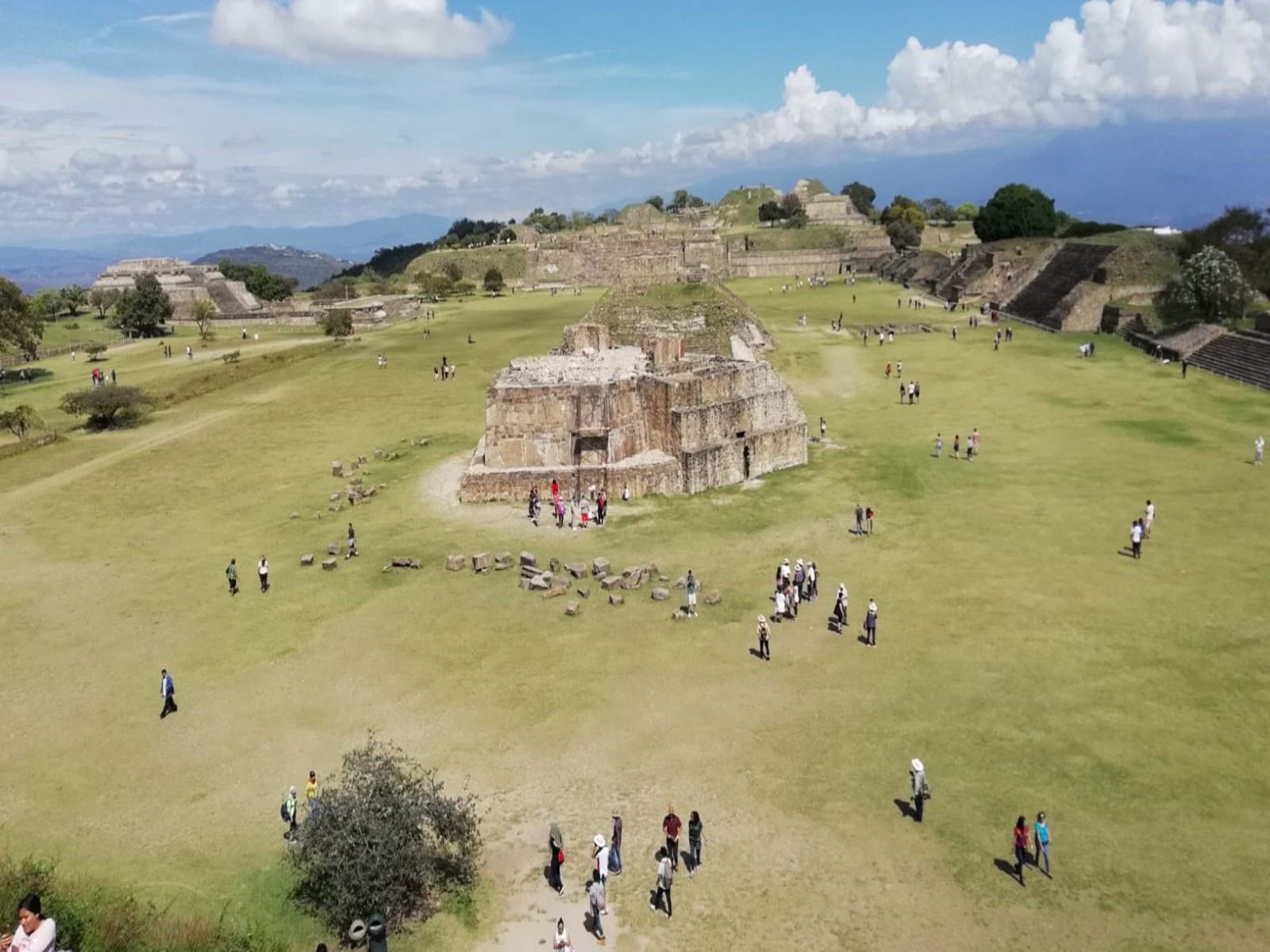 Eine große Grünfläche mit kurzem Gas, in Abständen stehen dort bauten aus längst vergangenen Zeiten. Es laufen Menschen über das Areal.