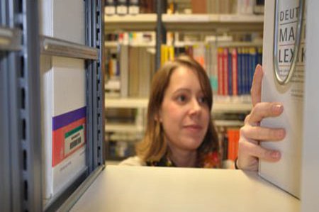 Eine Frau durchforstet die Regale der Bibliothek, der FH Kiel.