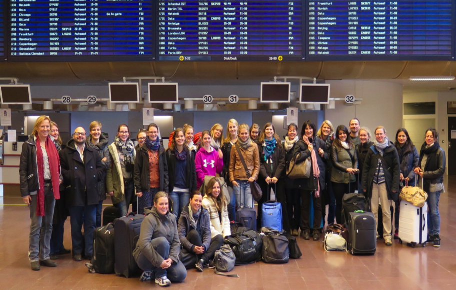 Eine Gruppe Studierender steht mit Sack und Pack in der Halle eines Flughafens.
