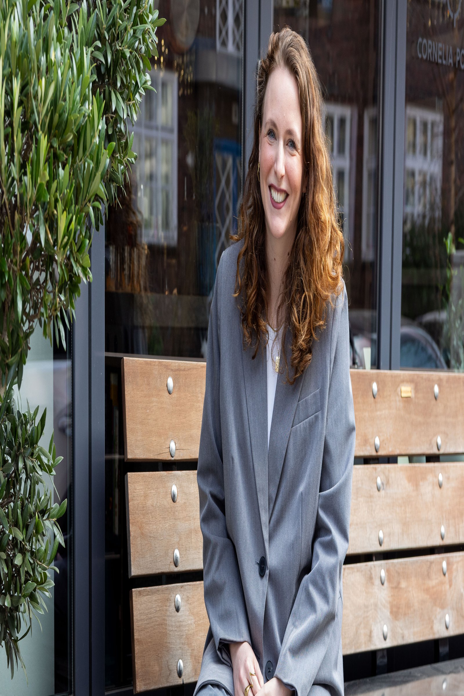 A woman is sitting on a bench next to a flowerpot