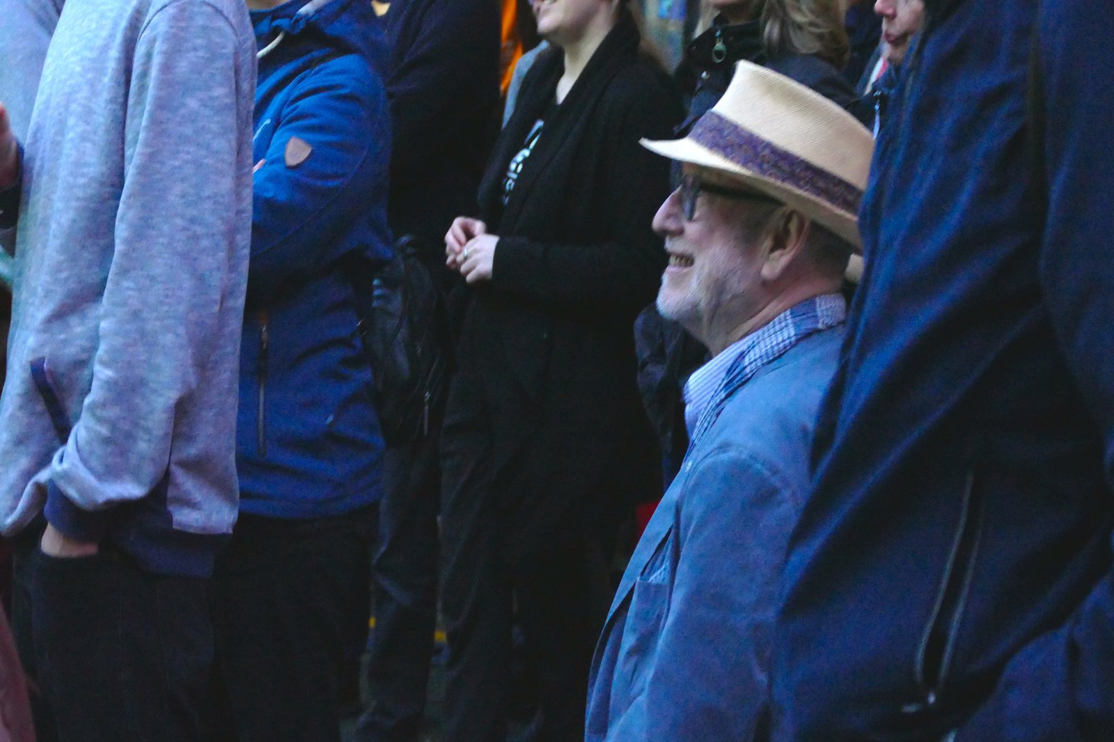 Ein Mann sitzt inmitten einer stehenden Menschenmenge.