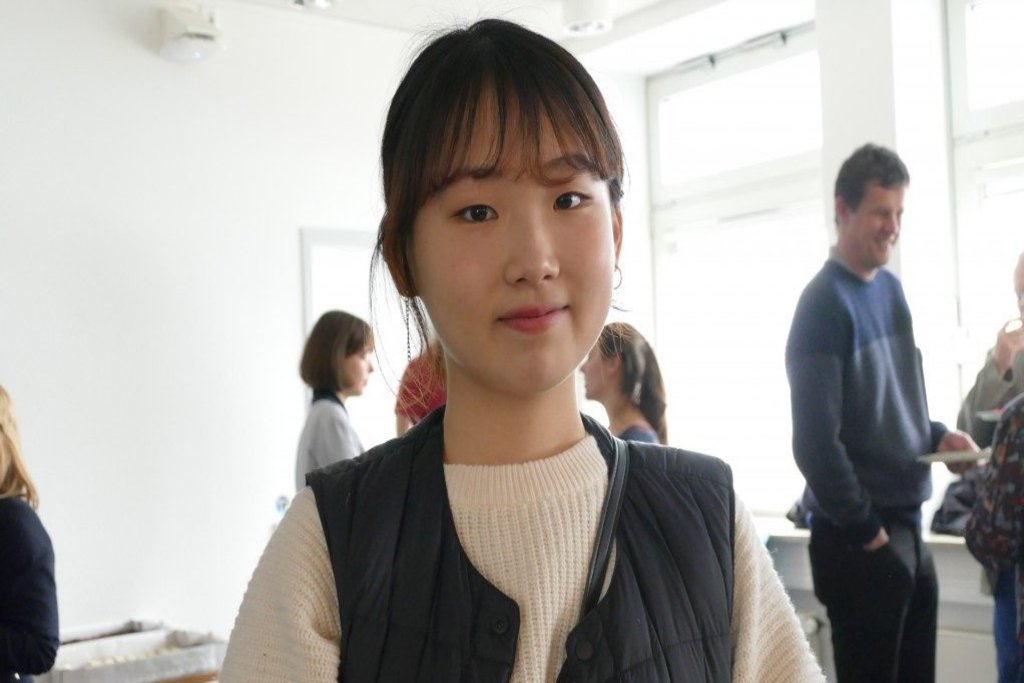 Eine Frau lächelt in einem Ausstellungsraum in die Kamera.