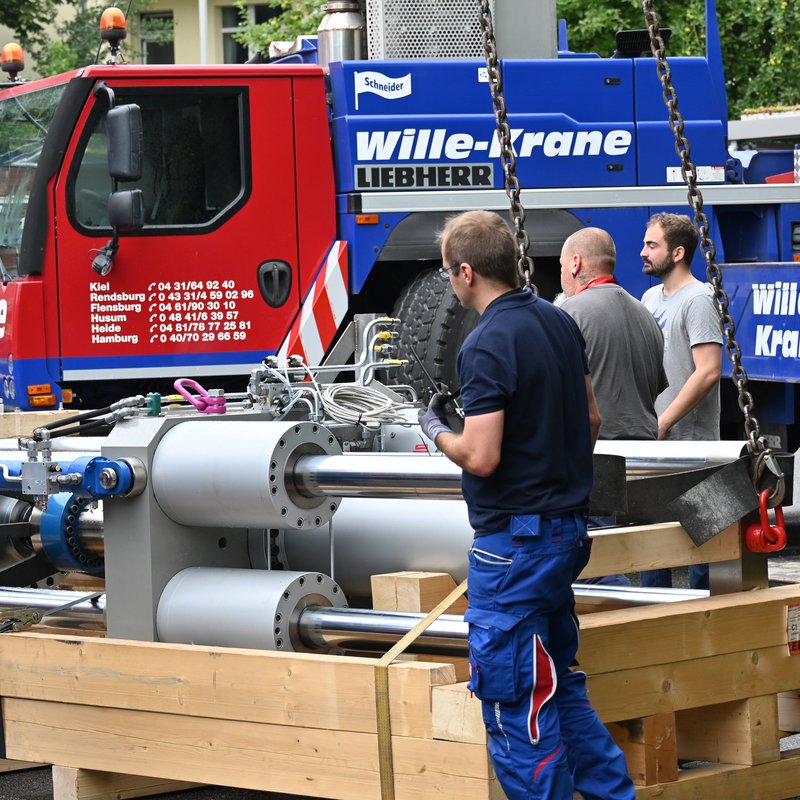 Blick auf die neue Prüfmaschine des Instituts für Bauwesen vor dem Ladekran