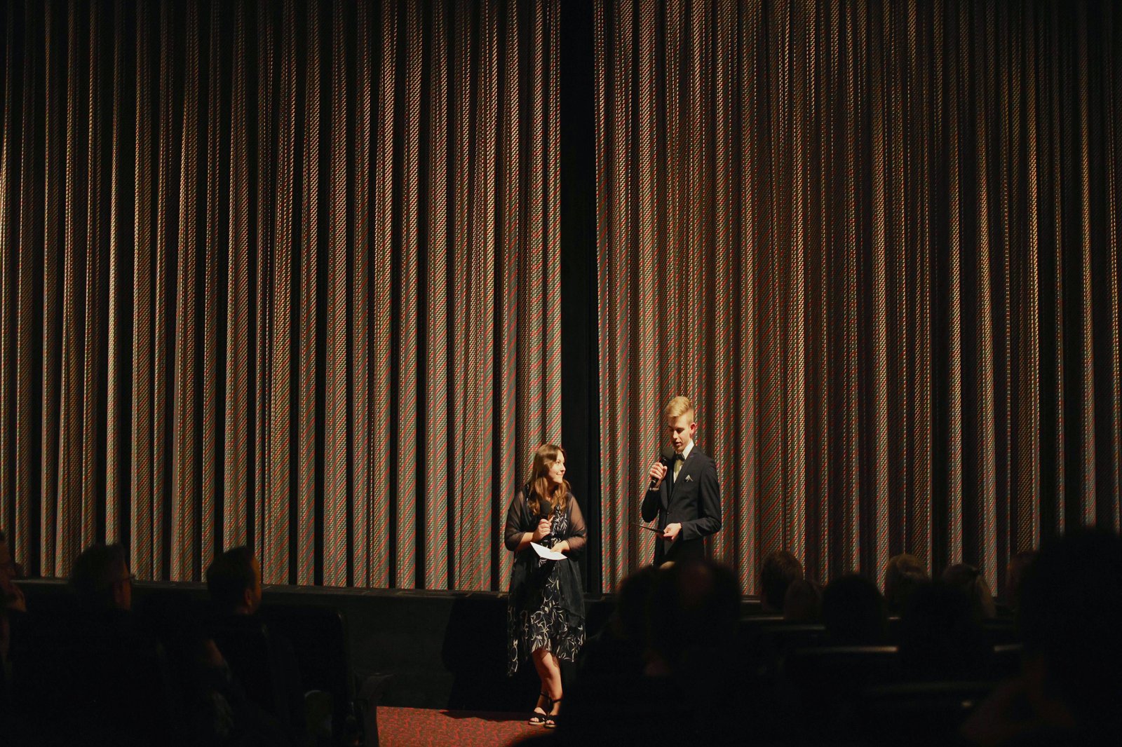 Zwei Personen vor einem geschlossenen Bühnenvorhang