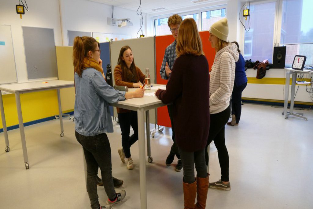 Fünf Studierende arbeiten an einem Stehtisch.