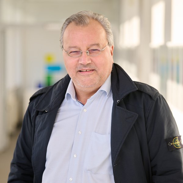 Tobias Specker Portrait eines Mannes in blauer Jacke in einem Flu an der HAW Kiel