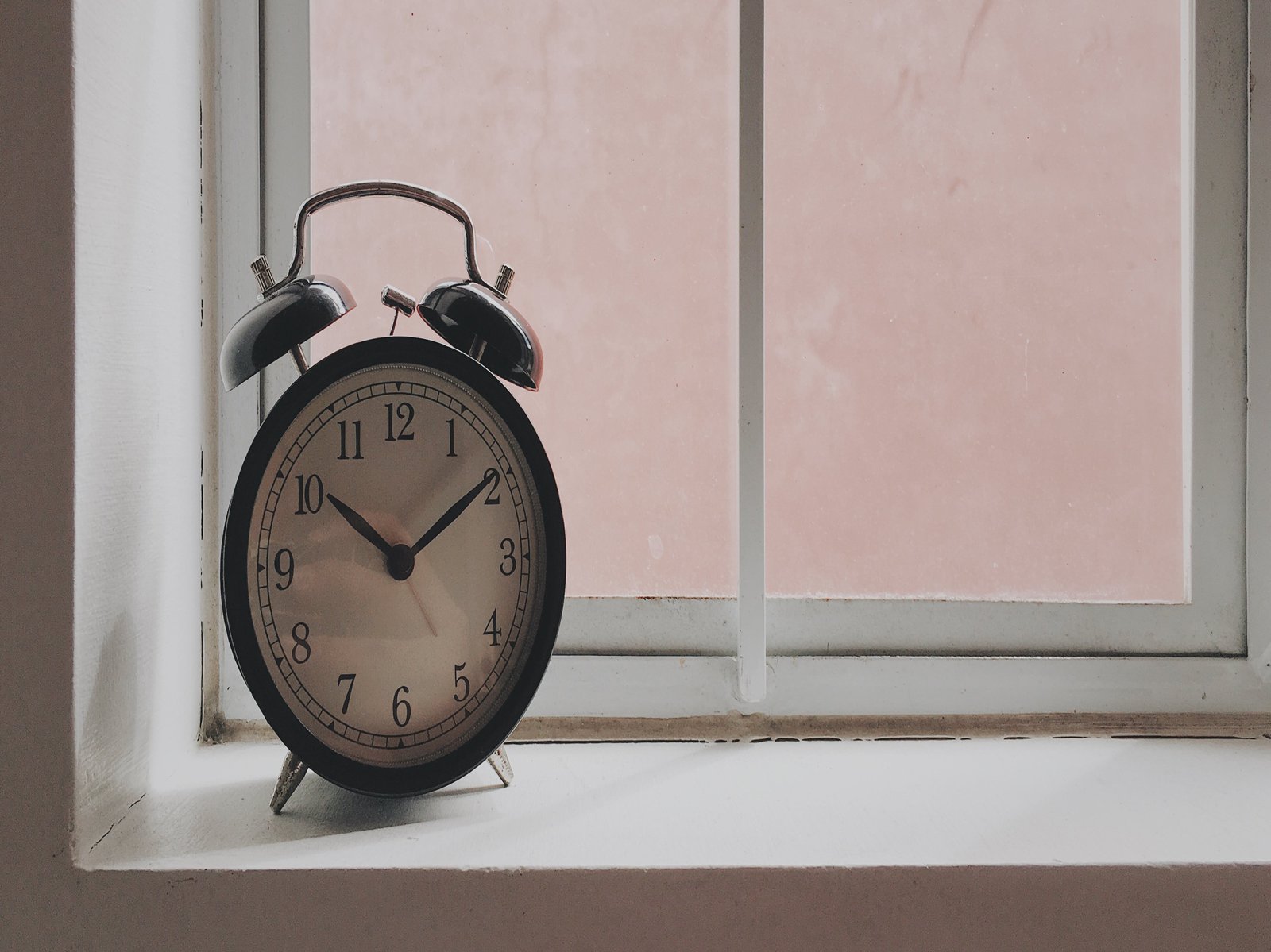 Das BIld zeigt einen alten Wecker, der auf einer Fensterbank steht.