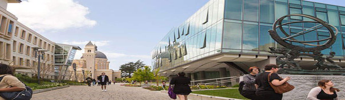 Ein Panoramabild von einem Campus. Es sind Gruppenstudierender und schöne Gebäude zu sehen.
