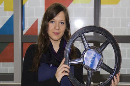 Eine Studentin hält eine schwarze Filmrolle neben ihre Schulter.