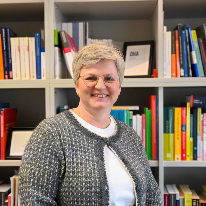 Eine Frau steht vor einem Bücherregal.