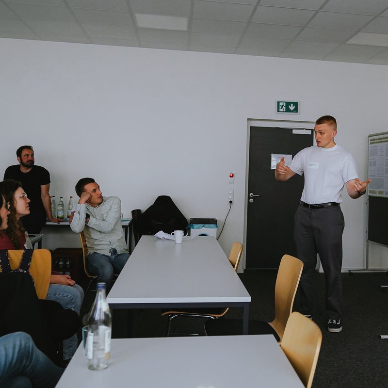 Ein junger Mann präsentiert ein Poster.