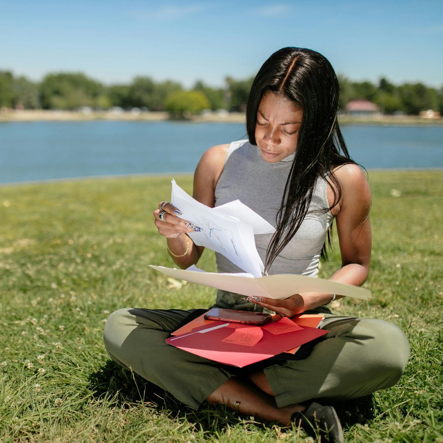 Junge Frau sitzt auf Wiese und liest.
