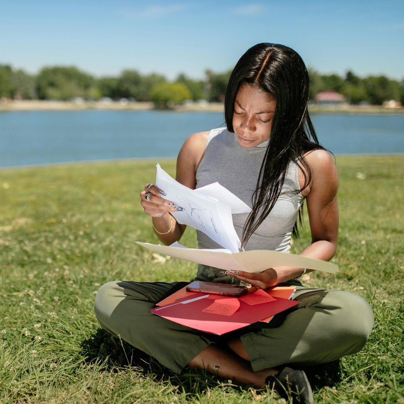 Junge Frau sitzt auf Wiese und liest.