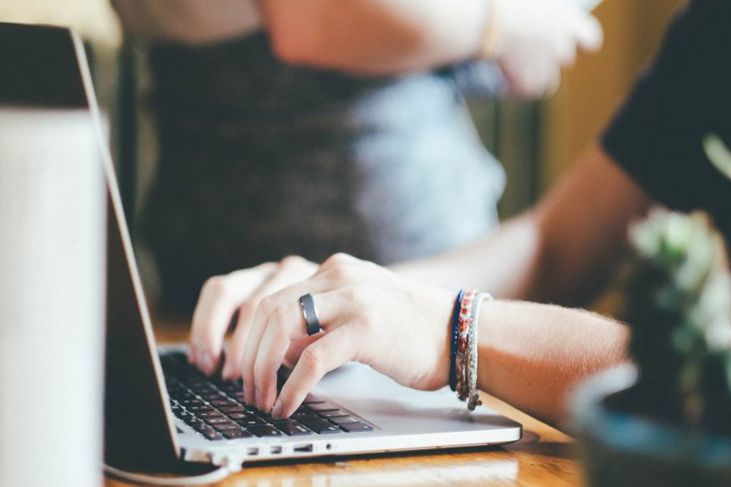 Zwei Hände arbeiten an der Tastatur eines Laptops.