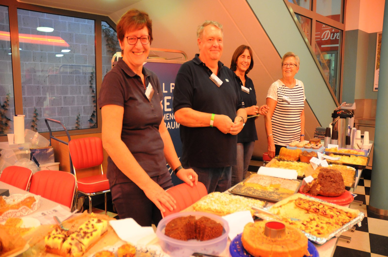 Drei Frauen und ein Mann stehen hinter dem Catering und bieten Speisen an.