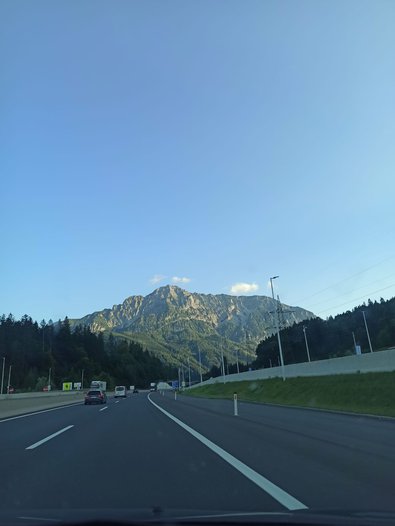 Bild von Jana auf dem Kofferaum sitzend bei der Anreise, Fotos von den ersten Eindrücken in Graz bei der Murinsel und eine Brücke, die beide Ufer in Graz verbindet