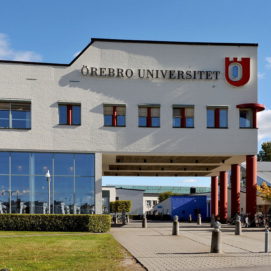 Ein weißes Hochschulgebäude vor blauem Himmel.