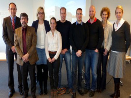 Die Projektgruppe versammelt sich vor der Leinwand, in einem Konferenzraum.