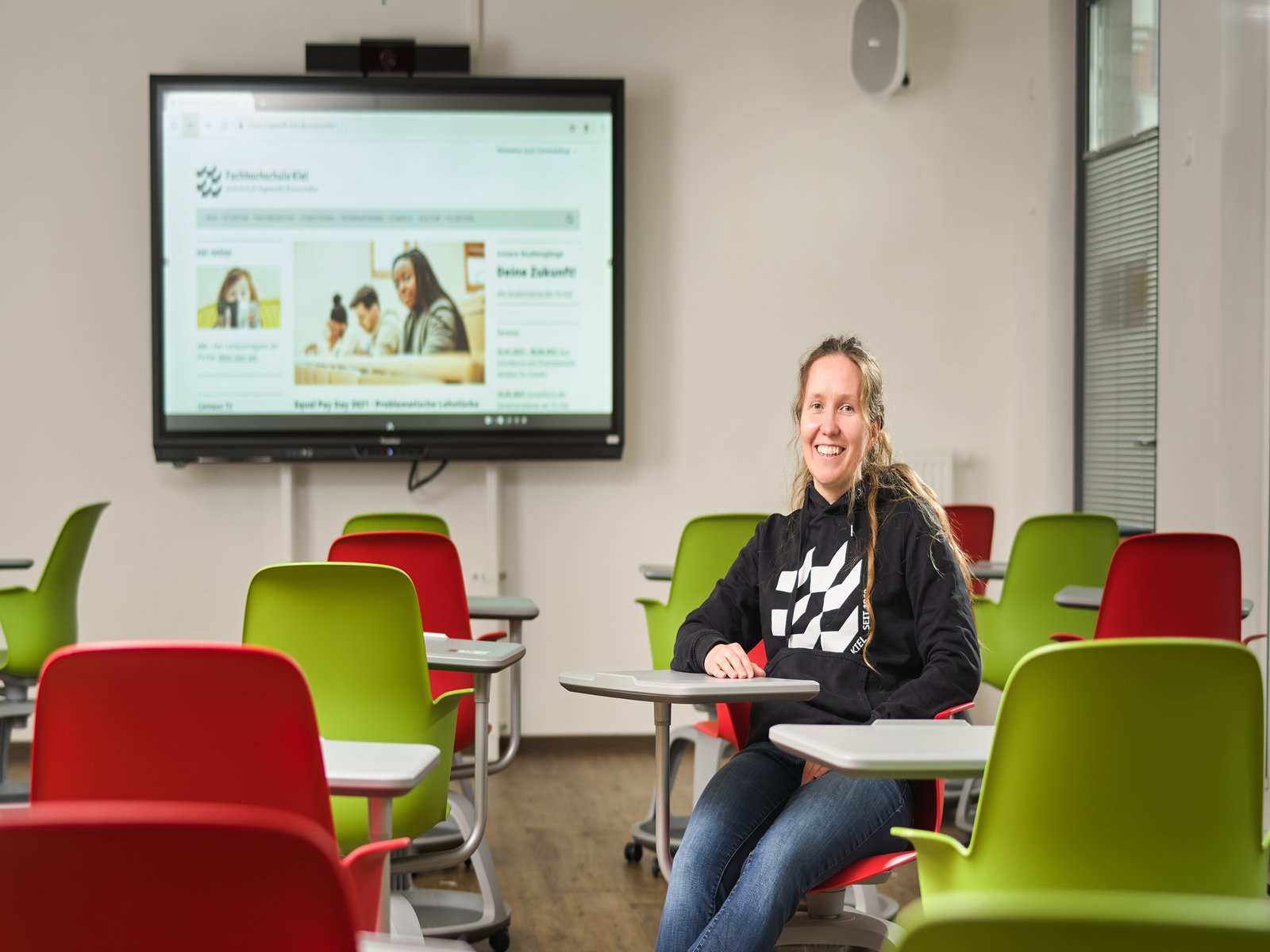 eine Frau auf einem Stuhl vor einem Monitor