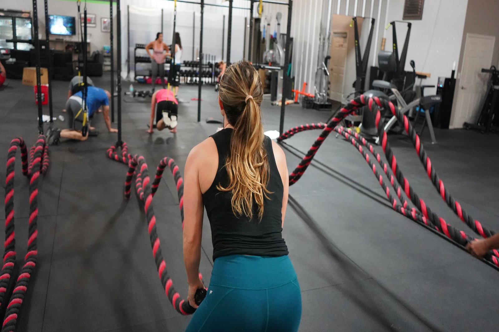 Eine FRau in einer Crossfitbox. Sie trainiert mit dicken Tauen.