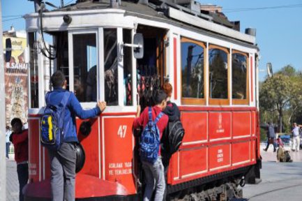 Drei Jungen halten sich außen an einer Straßenbahn fest.