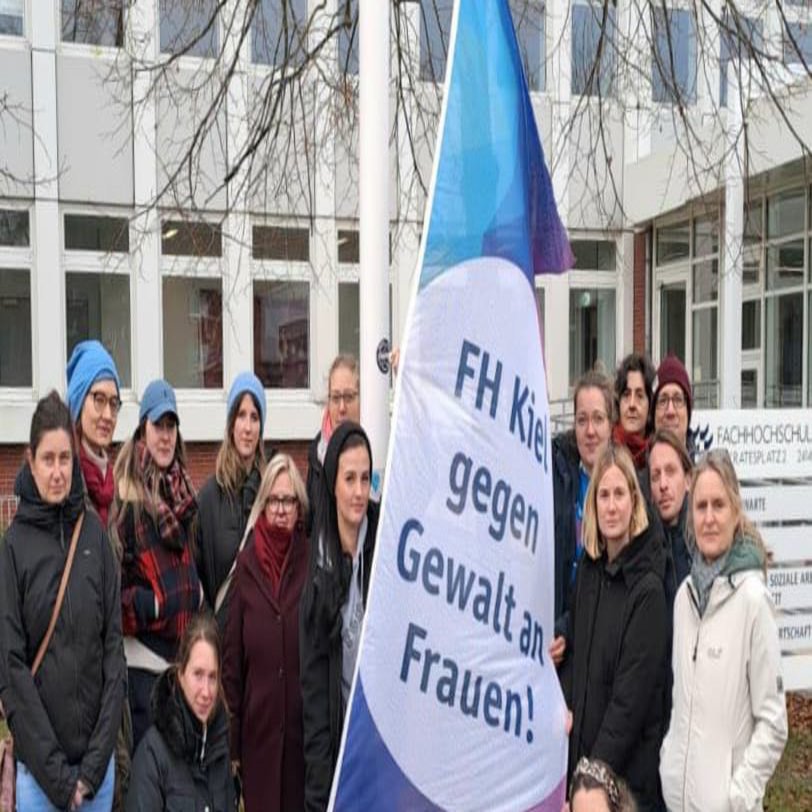 Das Bild zeigt Personen aus Zentralverwaltung und Gleichstellungsstelle sowie Doktorand*innen und die Diversitätsbeauftragte. Sie halten die Flagge gegen Gewalt an Frauen und Mädchen vor sich.