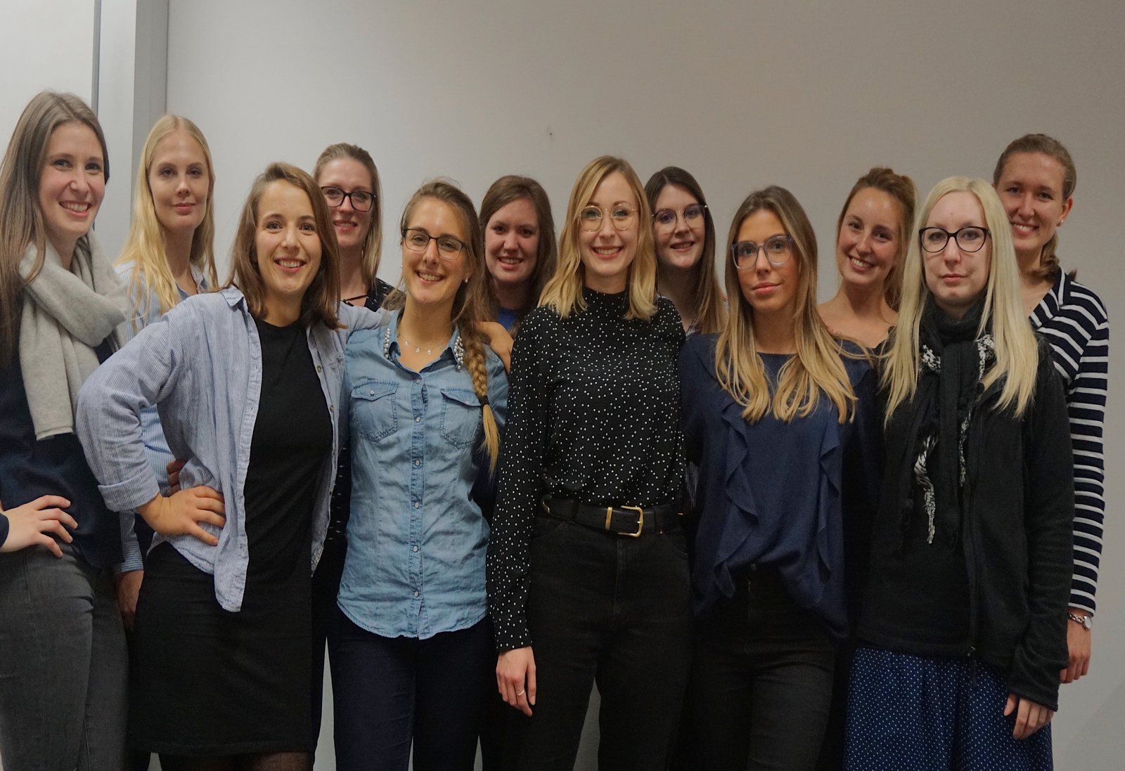 Eine Gruppe Studentinnen posiert vor einer weissen Wand.