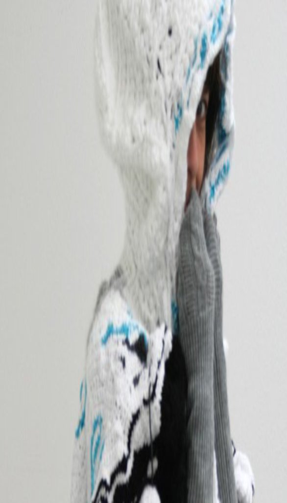 Eine Person kuschelt sich in einen Poncho, der wie eine Landschaft aussieht.