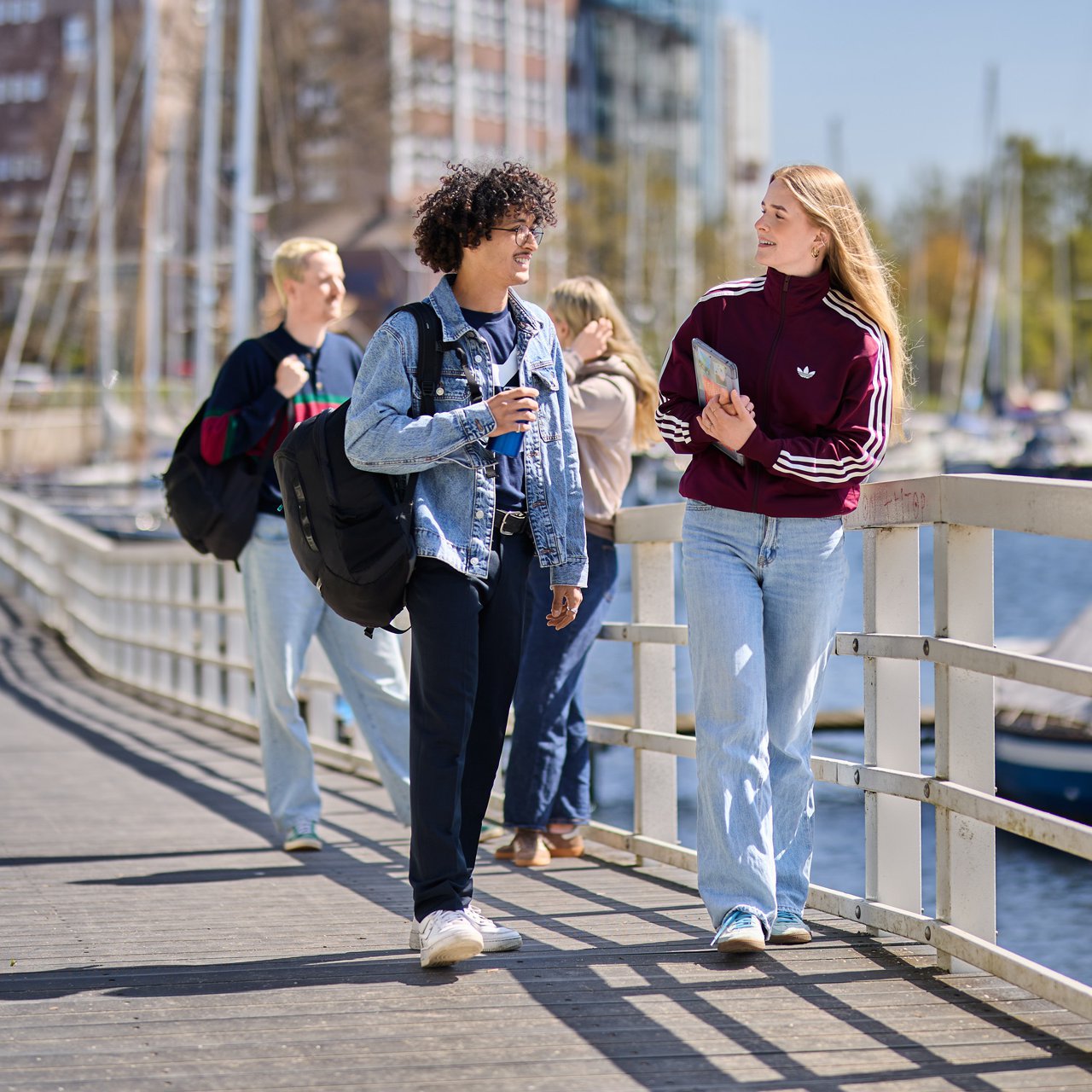 Students from Kiel University of Applied Sciences are walking along a boardwalk by the water and chatting
