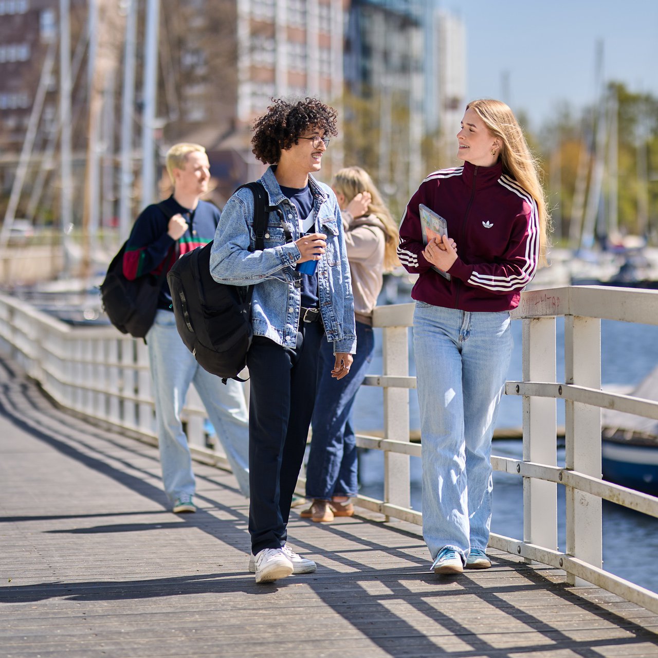 Studierende der HAW Kiel gehen auf einem Steg am Wasser und unterhalten sich