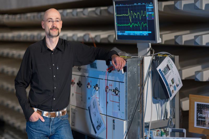 Ein Mann in schwarzem Hemd lehnt sich an einen Schaltwagen.