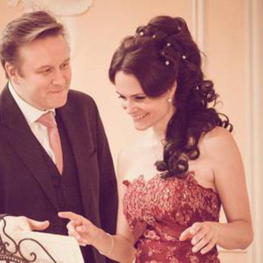 Eine Frau und ein Mann in festlicher Kleidung stehen vor einem Notenständer.