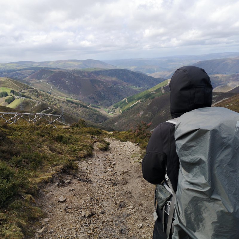 Person mit Rucksack blickt in die gebirgige Landschaft