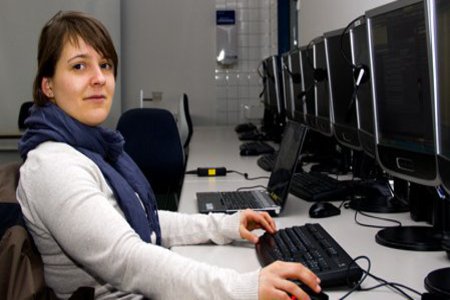 Eine Frau mit blauem Schal, sitzt in einem Computerlabor.