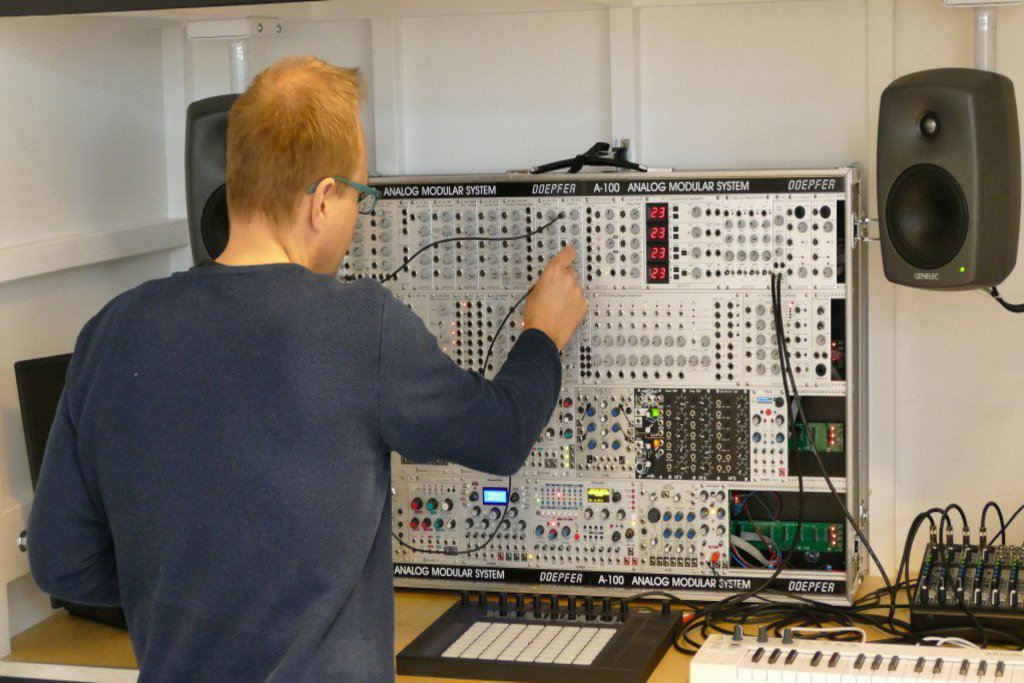 Ein Mann steht vor einem Schaltkasten und steckt ein Kabel um.