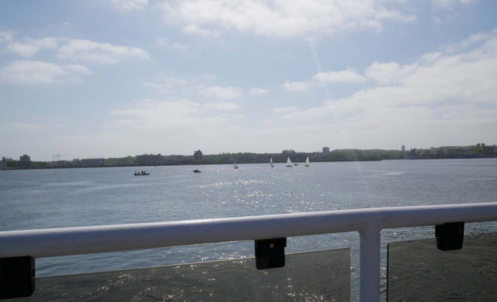 Eine ans Wasser endende Brüstung, im Hintergrund sieht man Segelboote umherfahren.