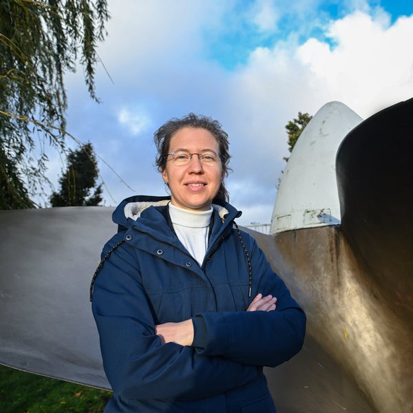 Eine Frau steht an einem sehr großen Schiffspropeller