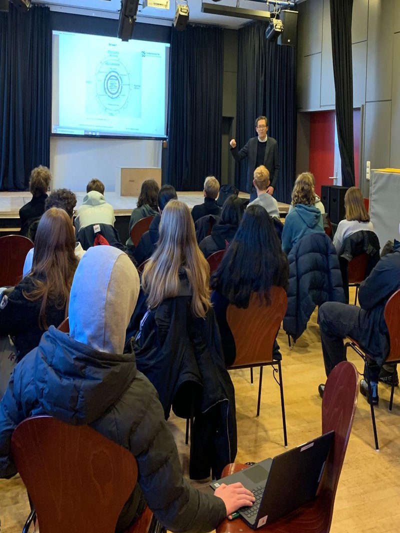 Prof. Dreßler vor einer Gruppe Schüler*innen