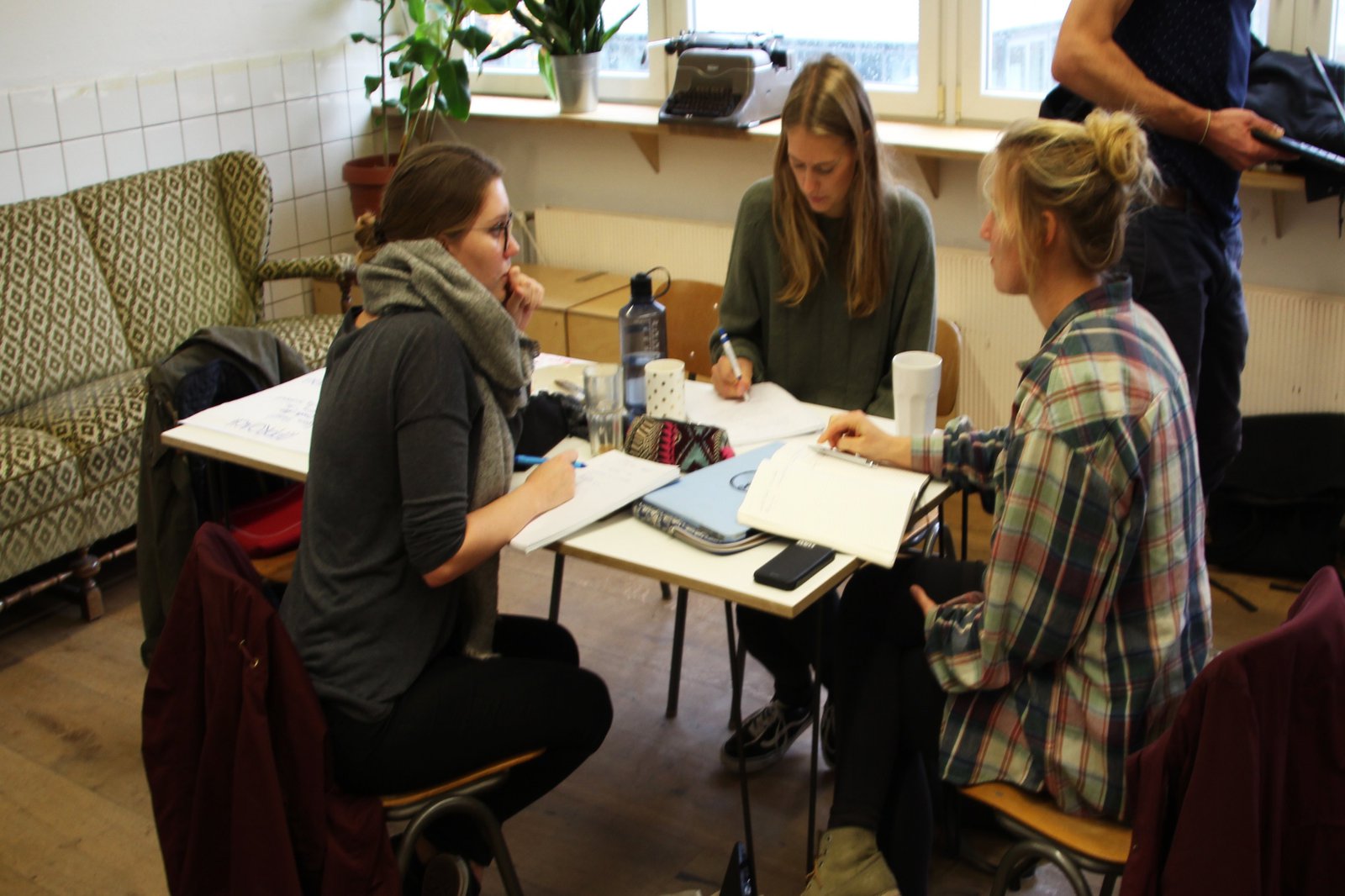 eine kleine Gruppe Studentinnen sitz grübeln vor ihren Unterlagen.
