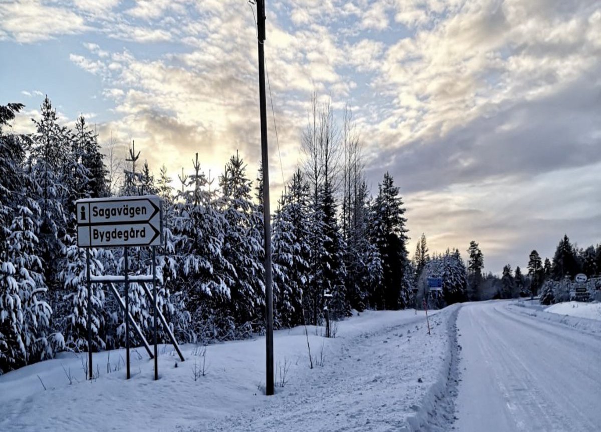 Eine zugeschneite Straße, im Hintergrund ist ein blauer Himmel mit einigen Wolken zu sehen.