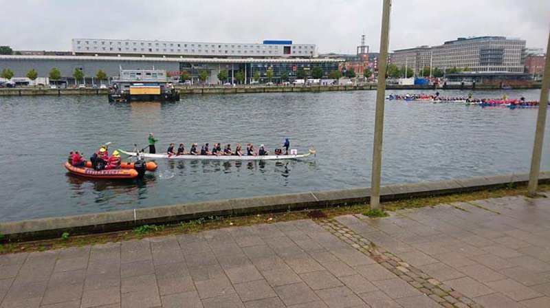 Mehrer Drachenboote stehen bei Nieselregenan der Startlinie.