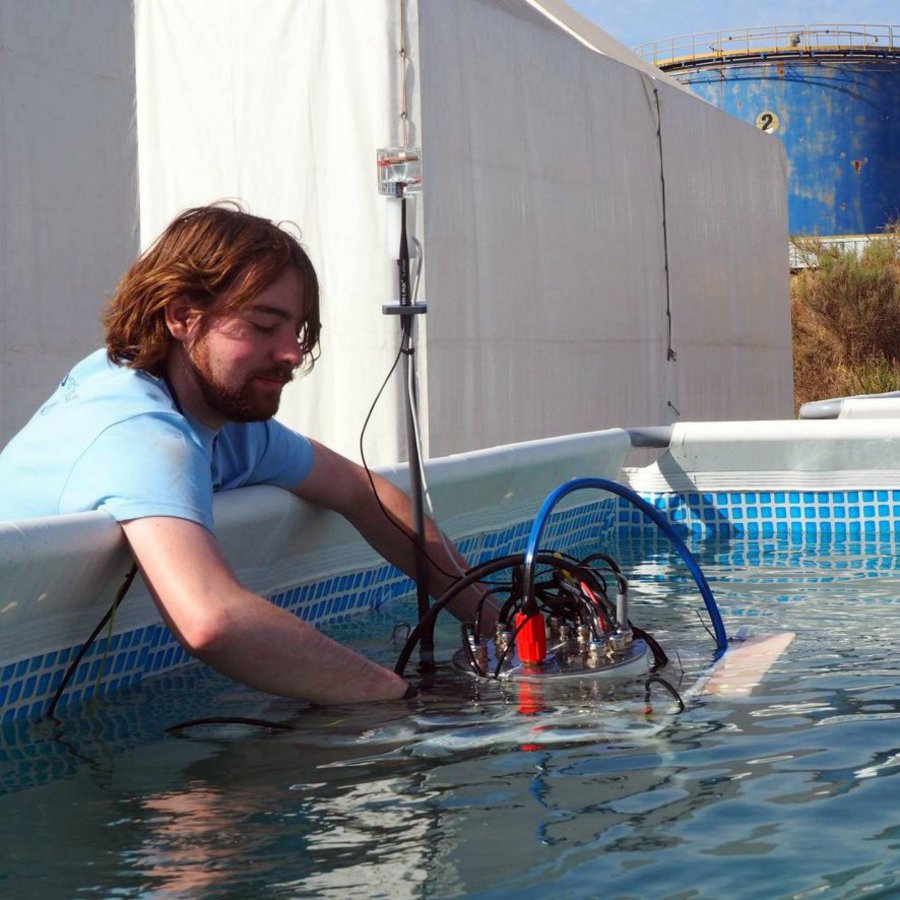 Ein Mann setzt eine Unterwassermaschine in einen Pool ein.