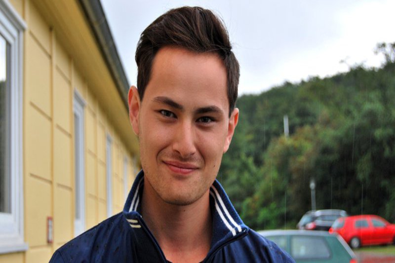 Ein Mann in einer blauen Ruder-Club Jacke schaut motiviert in die Kamera.