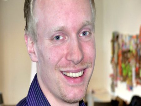 Ein Student schaut zufrieden in die Kamera.