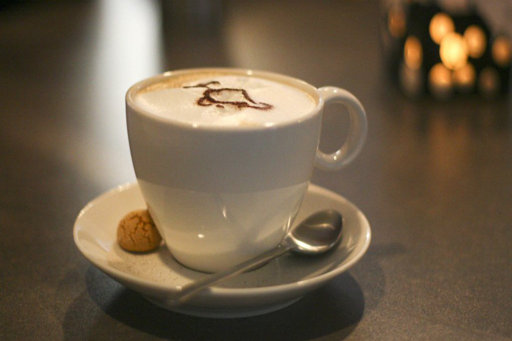 Auf einem schwarzen Tisch steht eine schöne Tasse Cappucino.