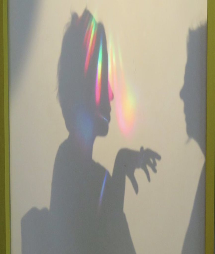 Der SChatten einer Person wird doch regenbogenfarbene Lichteffekte verziert.