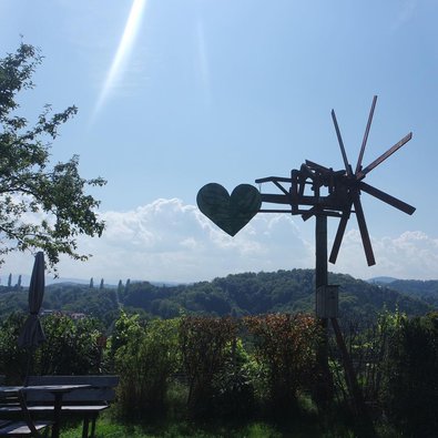 Ein Windrad vor blauem Himmel bei Sonnenschein, es ist ein Herz angebracht