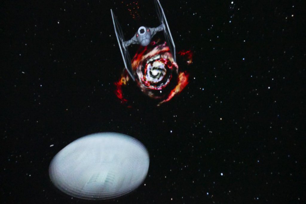 Ein Raumschiff in den Weiten des Weltalls. Im Hintergrund ist eine rote Galaxie zu sehen.